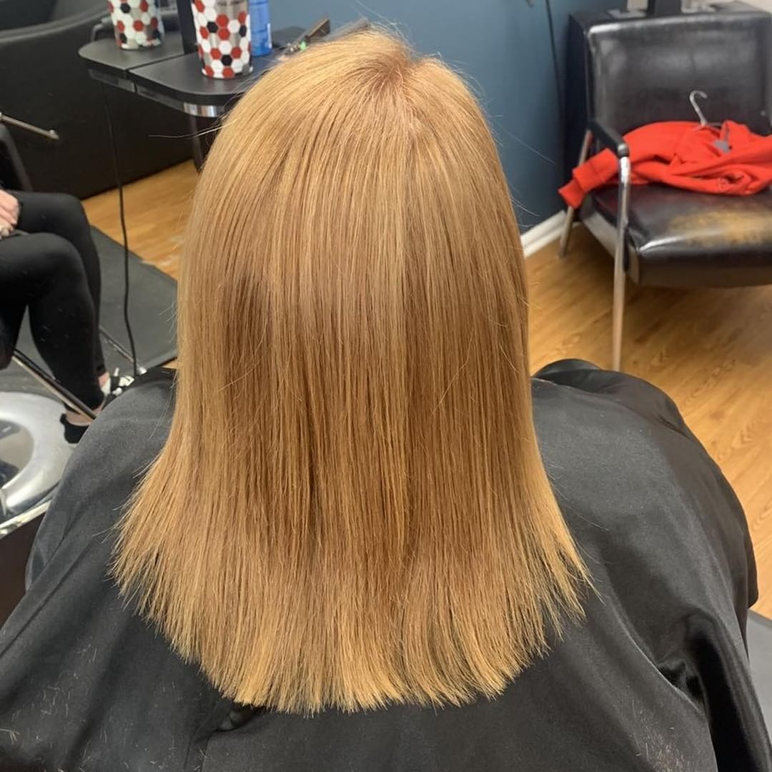 Back view of shoulder-length straight blonde hair after a trim in a salon chair