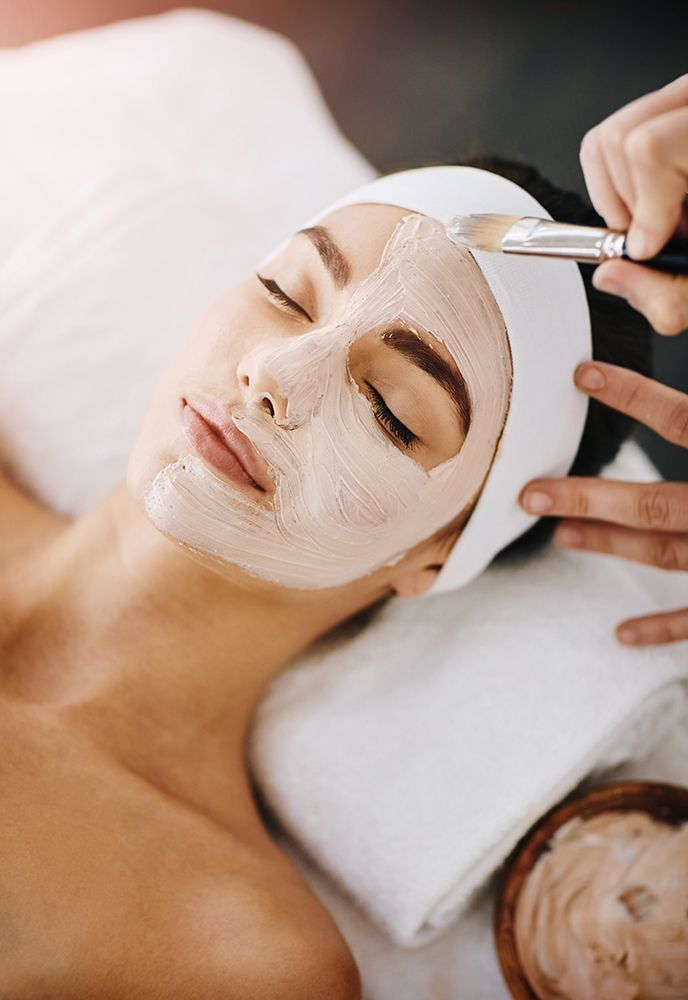 Woman receiving a facial mask treatment while lying on a spa bed