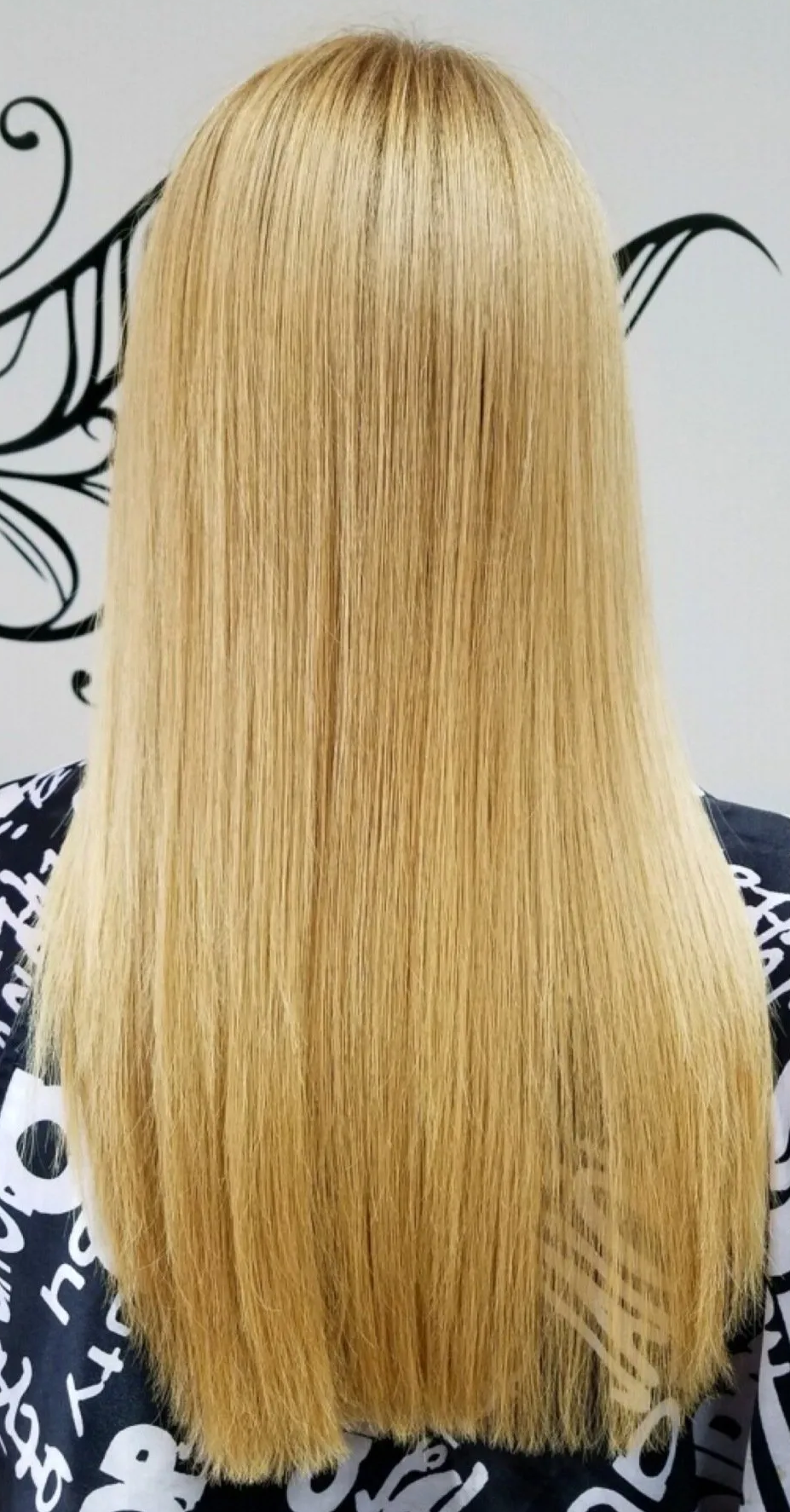 Back view of straight, long blonde hair against a black-and-white patterned background