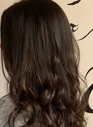 Dark wavy hair in loose curls against a light background