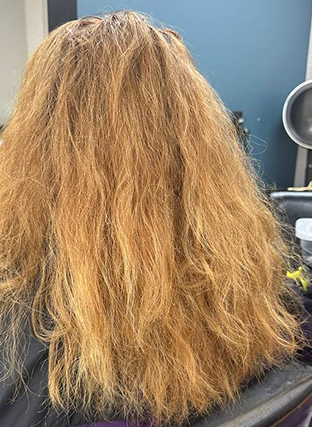 Back of a person with long, wavy light brown hair in a salon chair