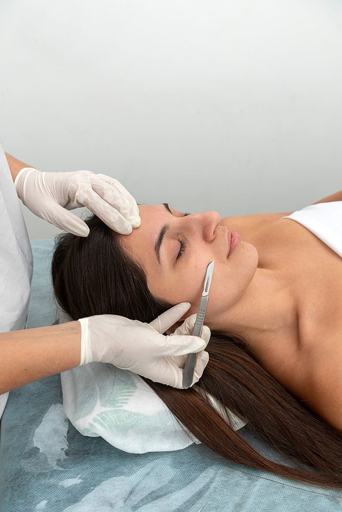 Facial treatment in progress, with gloved hands applying product to a woman lying on a spa bed.
