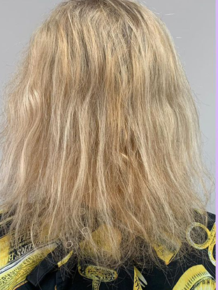 Back view of a person with shoulder-length blonde hair wearing a black jacket with yellow accents