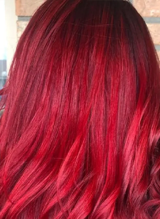 Close-up of long, wavy hair dyed deep red with dark roots.