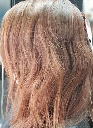 Close-up of wavy light brown hair with soft pink highlights at the ends
