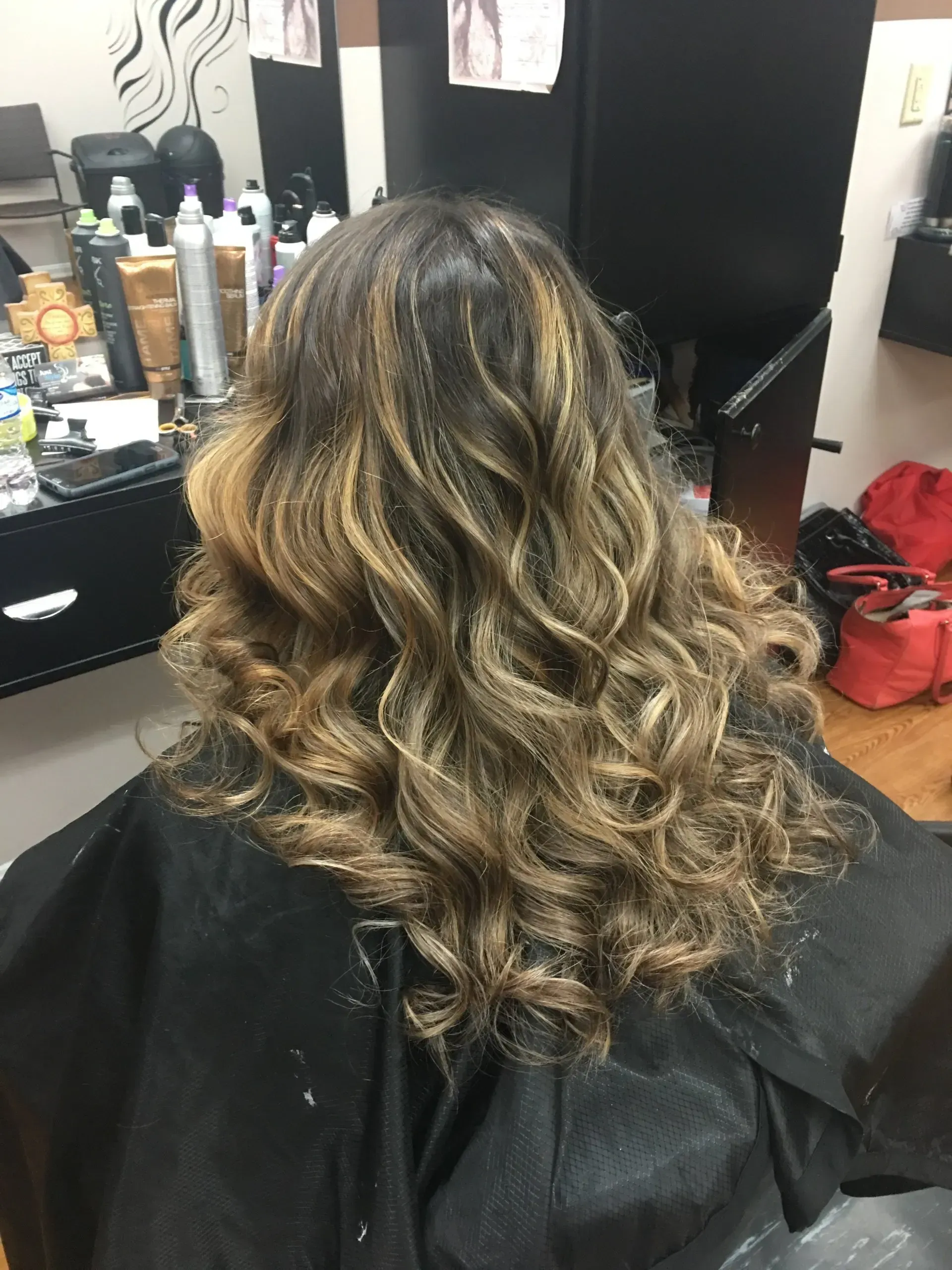 Curly highlighted brown hair styled in loose waves at a salon chair