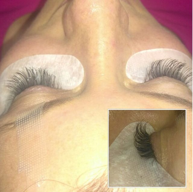Close-up of closed eyes with long eyelash extensions and white under-eye pads during application