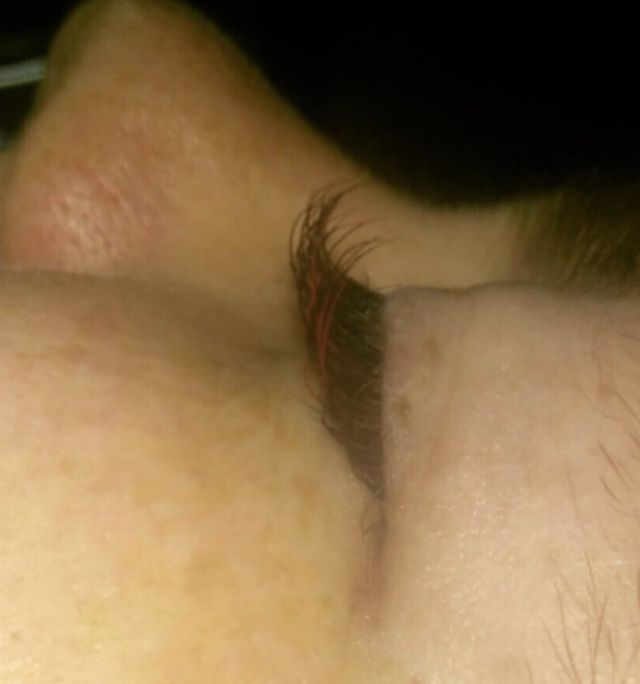 Close-up of a closed eye with brown eyebrow and pale skin in soft light