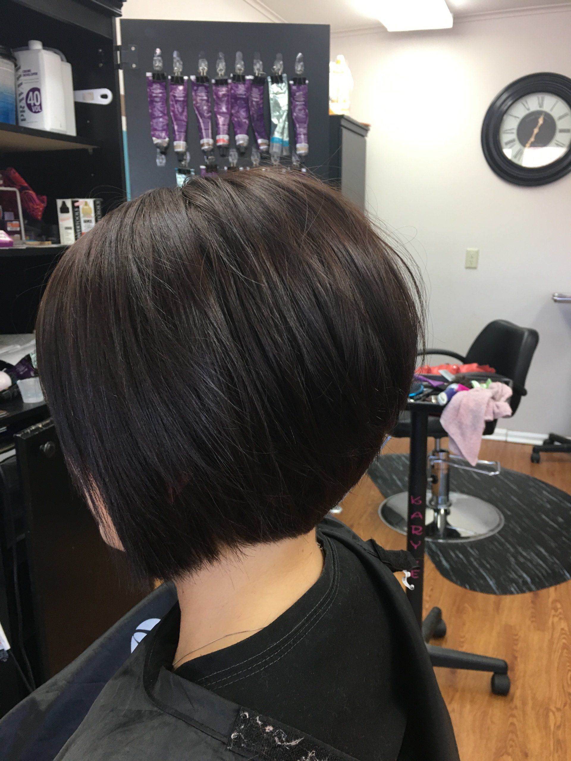 Short stacked bob haircut with dark brown hair in a salon.