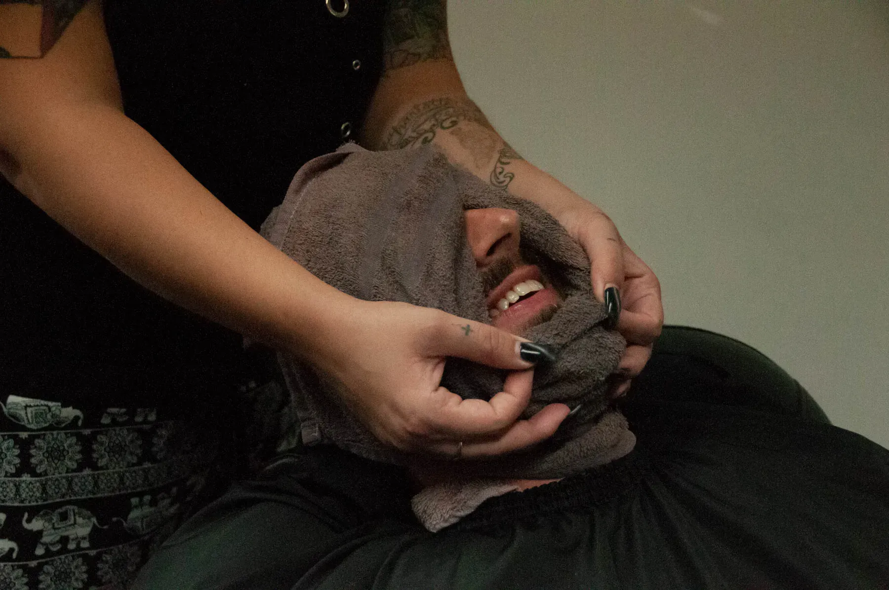 Person applying makeup to another person's face in a dim indoor setting.