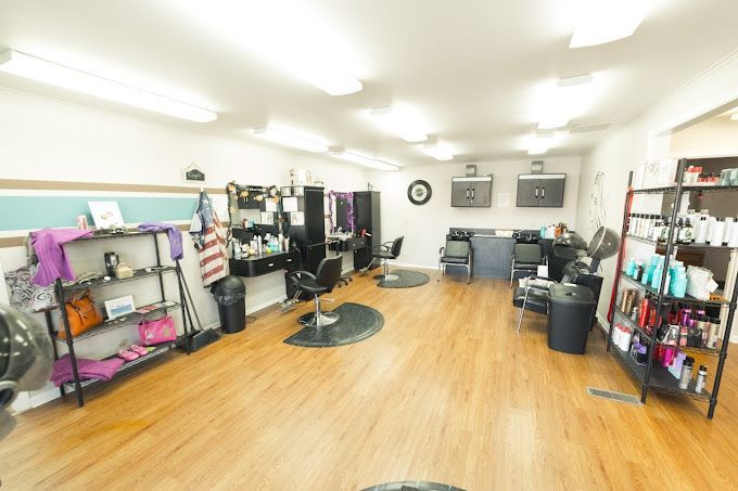 Bright salon interior with wooden floors, styling chairs, mirrors, and product shelves.