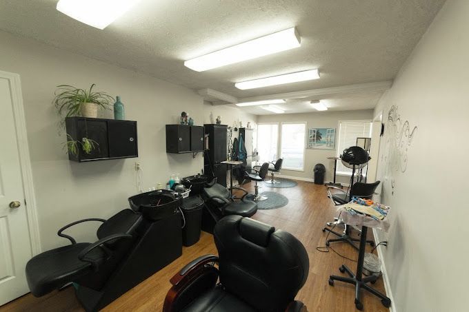 Barbershop interior with black chairs, wall shelves, mirrors, and bright overhead lights