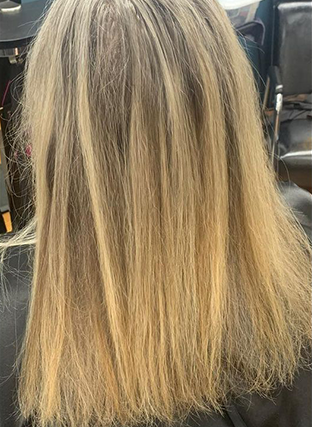 Blonde hair with dark roots, styled straight and shoulder-length in a salon chair.
