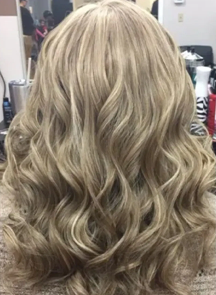 Long wavy blonde hairstyle viewed from the back in a salon setting